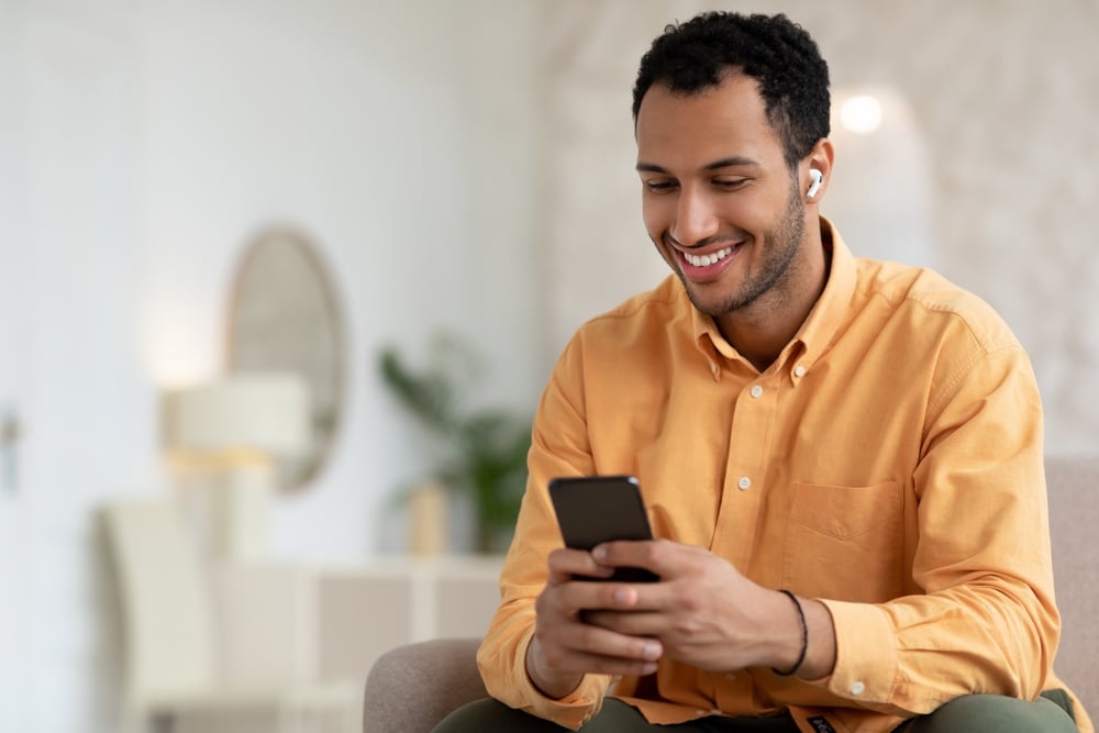 A smiling young man checking his phone