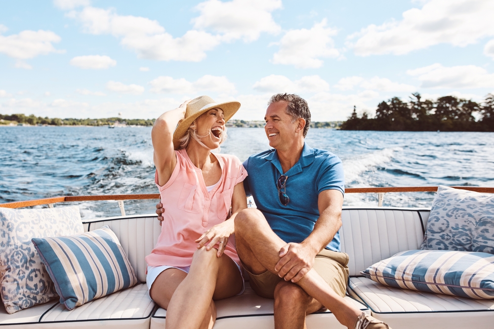 A laughing happy couple looking at each other, on a boat in the summer