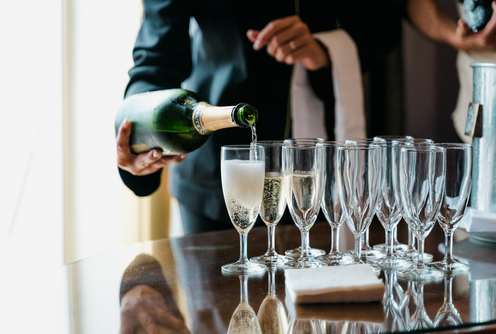 A waitress pouring champagne into glasses at a party. 